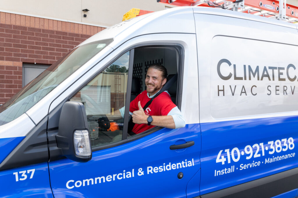 ClimateCare Tech sititng in a company vehicle, smiling and giving a "thumbs up"